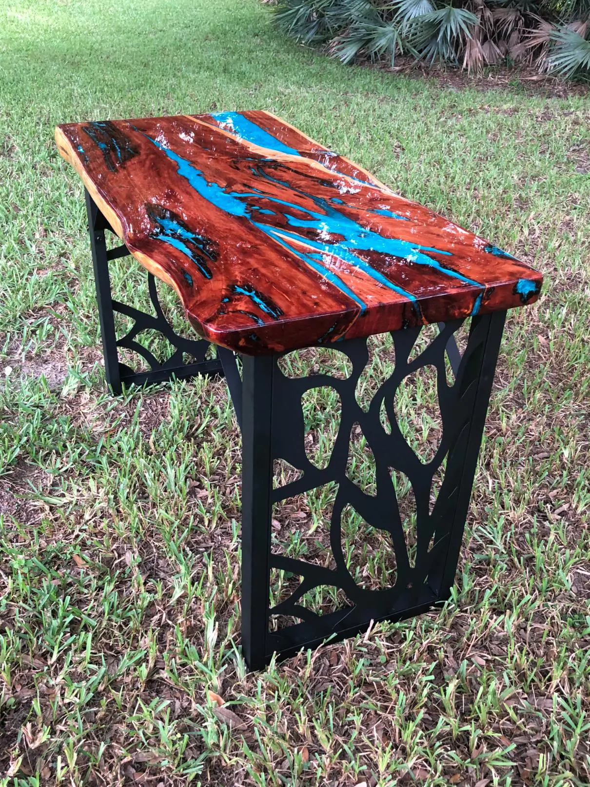Artistic wooden bench with intricate black metal legs.