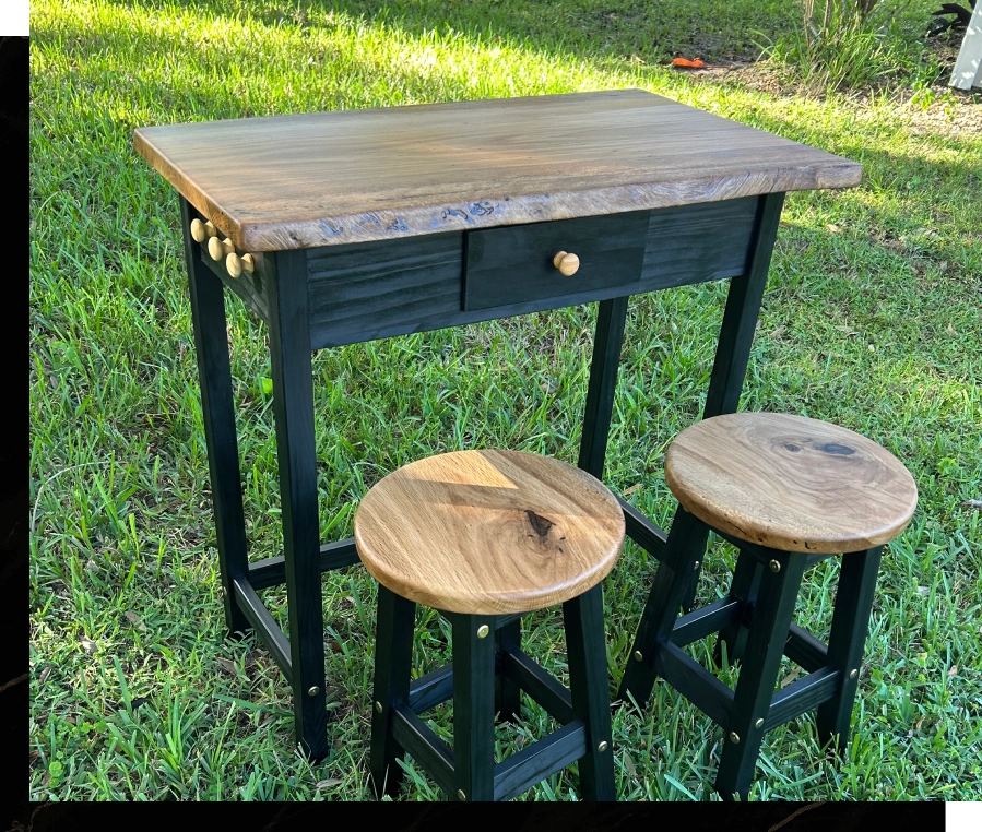 Rustic wooden bar table with two matching stools on green grass.