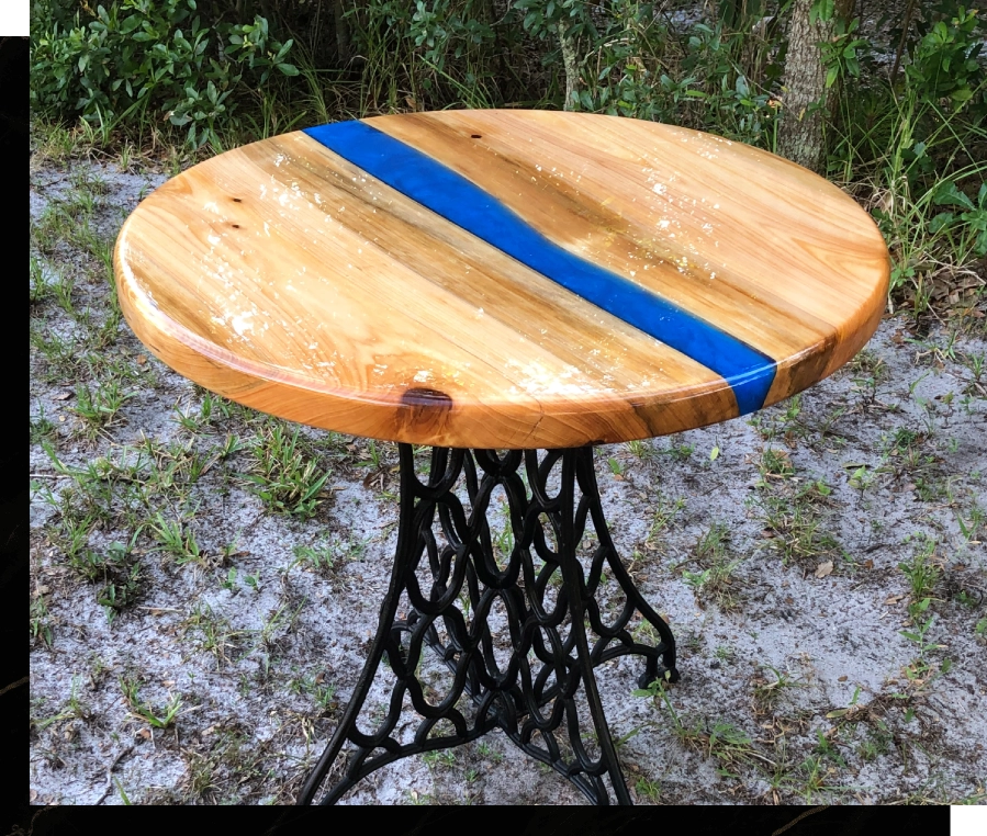 Round wooden table with a blue resin river and black metal base.
