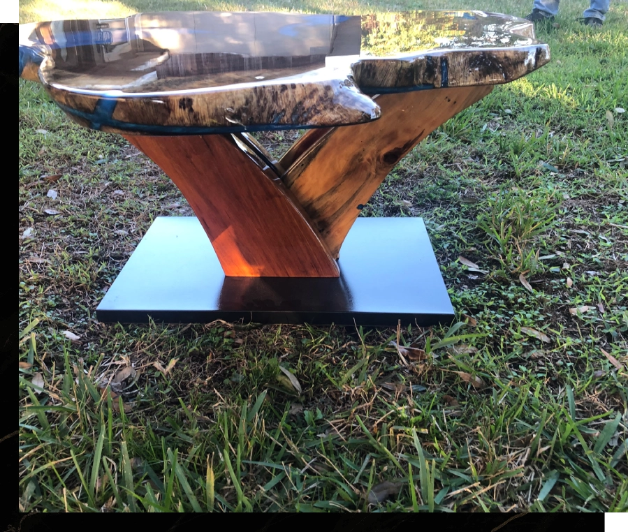 Wooden and resin table with artistic design on grass.