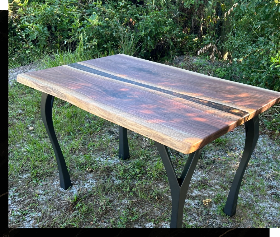 Rustic wooden table with metal legs outdoors on grass.