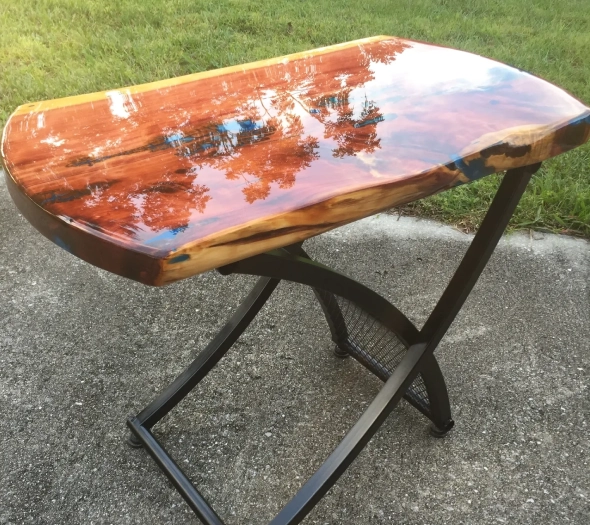 A wooden table with a glossy resin-coated surface outdoors.